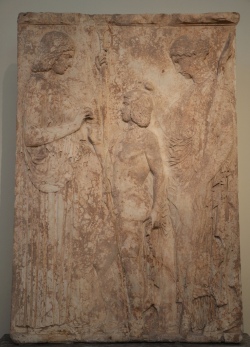This is the largest and most important votive relief found at Eleusis. It represents the Eleusinian deities in a scene of mysterious rituel. On the left Demeter, clad in a peplos and holding a scepter in her left hand, offers ears of wheat to Triptolemos, son of Eleusinian king Keleos, to bestow on mankind. On the right Persephone, clad in a chiton and mantle and holding a torch, blesses Triptolemos with her right hand. This relief, dating to c. 440-430 BCE, was apparently famous in antiquity and was copied in the Roman period. (Archaeological Museum of Athens, Greece) 